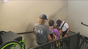 Firefighters carry residents after elevator breaks