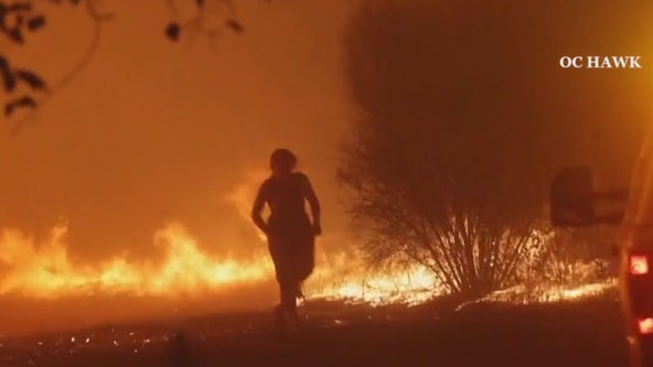 Woman walks through wildfire flames