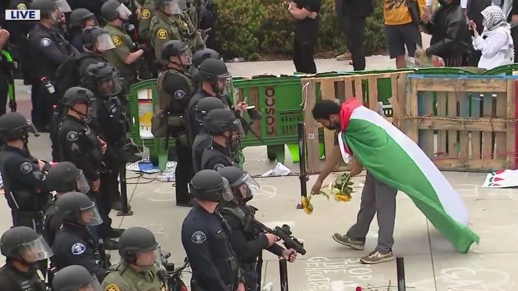 Man in Palestine flag leaves flowers for cops