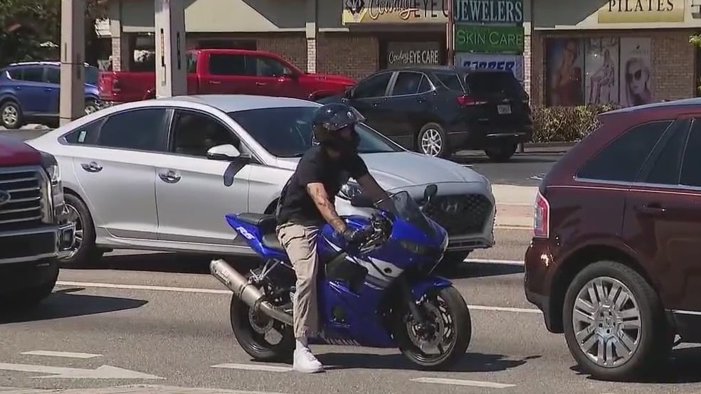 Motorcyclist pushes man in wheelchair across road