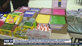 Autism R.E.C. holding backpack and school supply giveaway