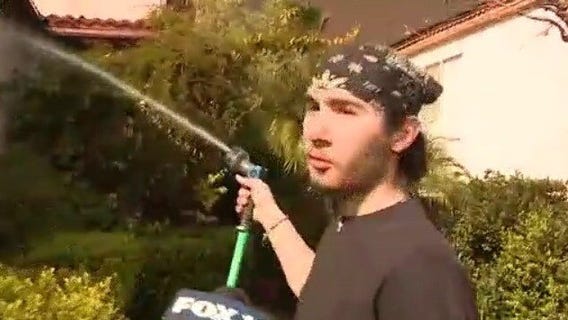 Homeowner uses hose to wet home as fire nears