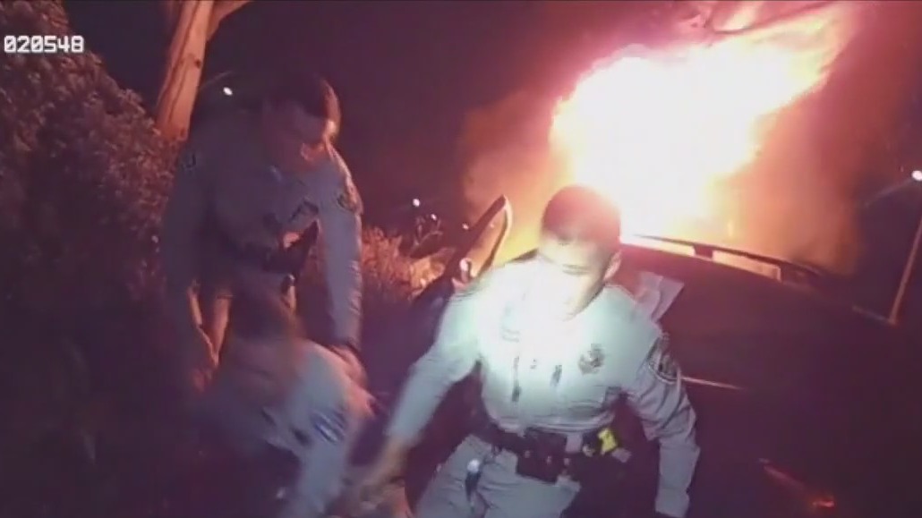 Officers rush in to save man in burning car