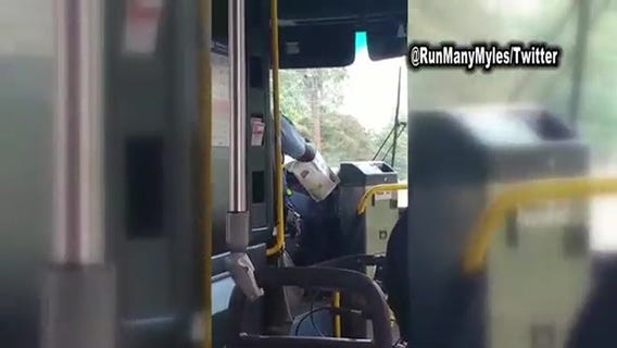 Metro bus driver reads newspaper while driving