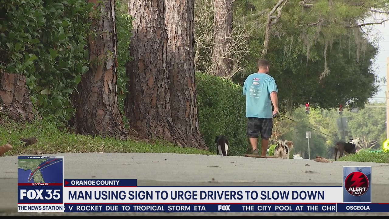 Man using sign to urge drivers to slow down