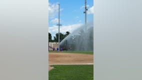 Firefighter sprays baseball field after stray ball hits car
