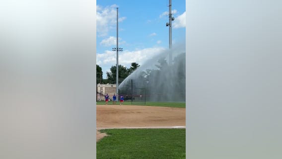 Firefighter sprays baseball field after stray ball hits car