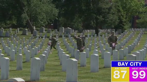Volunteers place flags on graves for Memorial Day