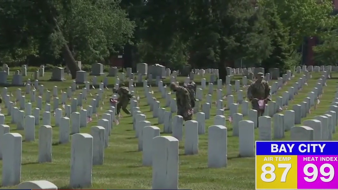 Volunteers place flags on graves for Memorial Day