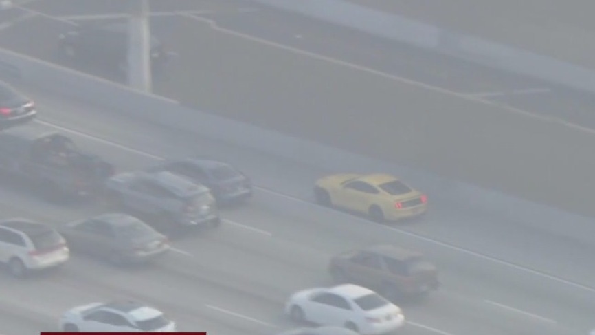 Yellow Ford mustang weaves through LA traffic