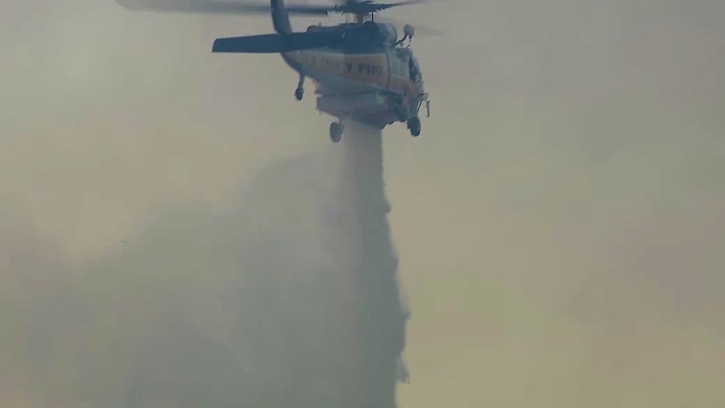 Helicopter dumps water over Hughes Fire in Castaic