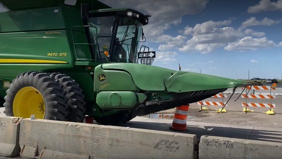 Driver of combine ignores signs, drives over construction barrels