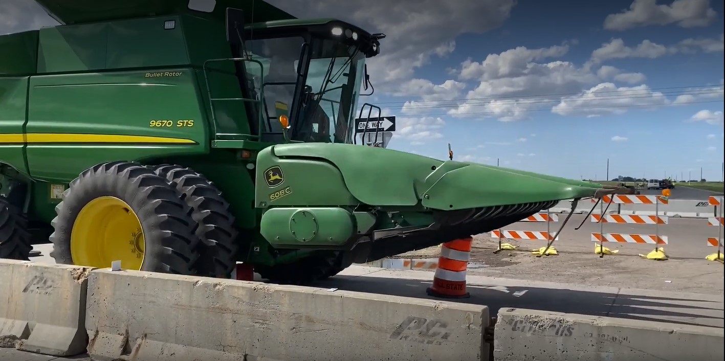 Driver of combine ignores signs, drives over construction barrels