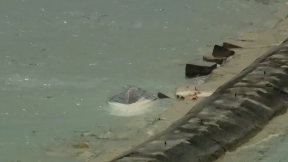 Capsized boat located on break wall amid search for missing woman
