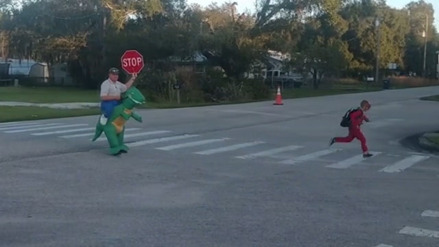 Manatee County deputy, dressed as T-Rex, stays in character as he directs traffic at school