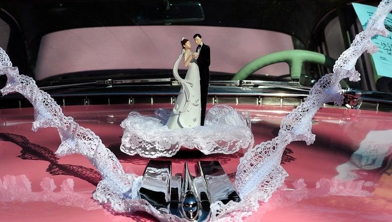 SANTA FE, NM - JULY 4, 2017: A vintage bride and groom wedding cake topper adorns the hood of a pink 1955 Cadillac Series 62 at a Fourth of July classic car show in Santa Fe, New Mexico. (Photo by Robert Alexander/Getty Images)