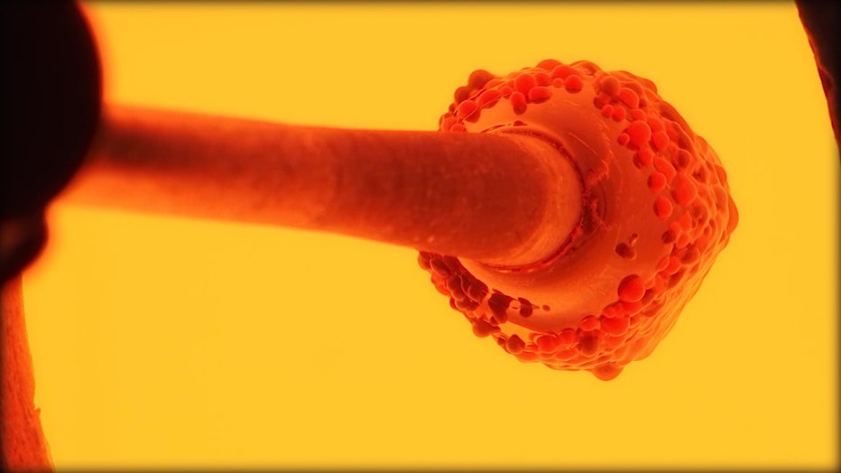 A photo showing molten glass on a pole, inside a glass furnace