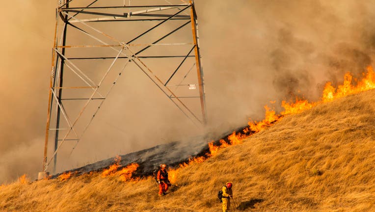 TOPSHOT - Firefighters set a back fire along a hillside near PG&E power lines during firefighting operations to battle the Kincade Fire in Healdsburg, California on October 26, 2019. - US officials on October 26 ordered about 50,000 people to evacuate parts of the San Francisco Bay area in California as hot dry winds are forecast to fan raging wildfires. (Photo by Philip Pacheco / AFP) (Photo by PHILIP PACHECO/AFP via Getty Images)