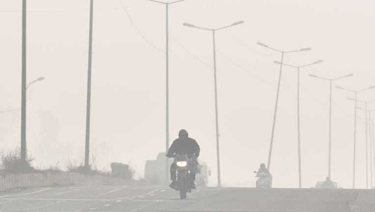FILE - A man rides a motorcycle amid heavy smog on a winter morning, at Zakhira, on November 30, 2019 in New Delhi, India.