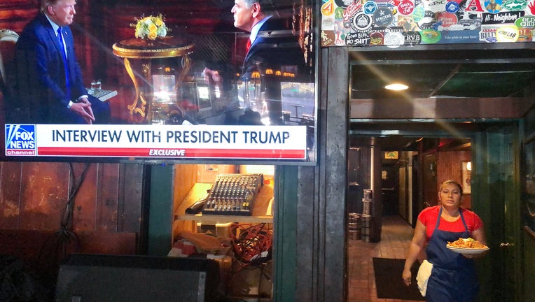 FILE - President Donald Trump’s pre-game Super Bowl interview with Fox News host Sean Hannity is broadcast in a bar on February 2, 2020 in Washington, DC.