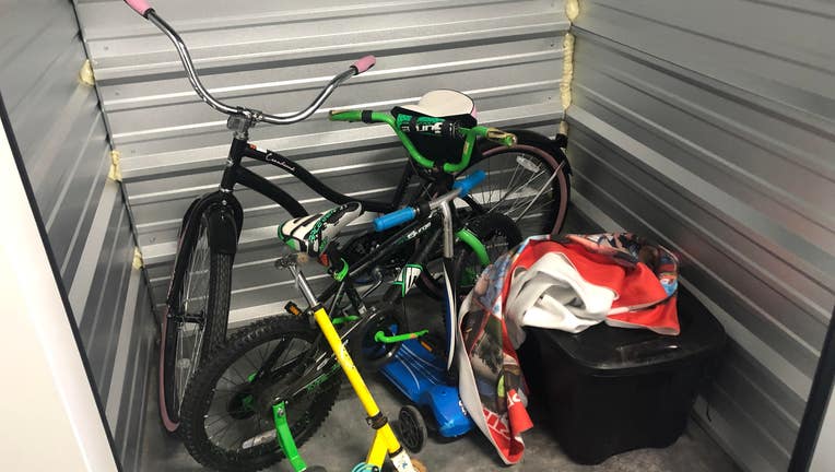 Storage unit with two bikes, a scooter, a bin, a couple of blankets