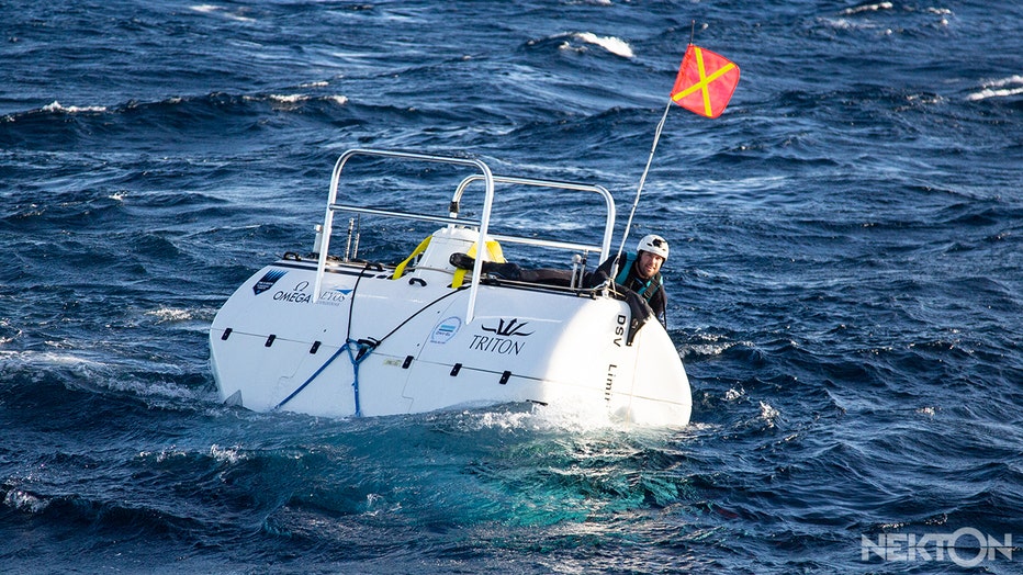 A safety swimmer on top of the Limiting Factor submarine just before it dives into the Mediterranean Sea during the sea trials in January 2020 for the upcoming First Descent: Midnight Zone mission in the Indian Ocean.