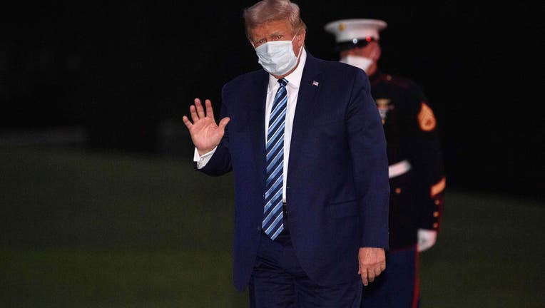 Photo of US President Donald Trump waves as he arrives at the White House wearing a facemask upon his return from Walter Reed Medical Center, where he underwent treatment for COVID-19, in Washington, DC, on October 5, 2020.