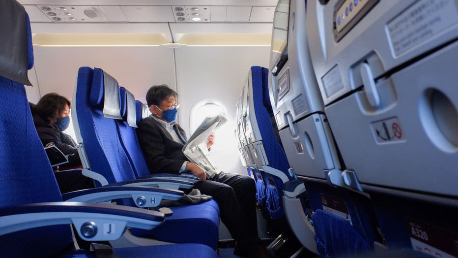 A passenger wearing a face mask seen reading a news paper