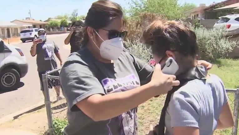 A volunteer with Elevate Phoenix gives a graduation stole to a senior.