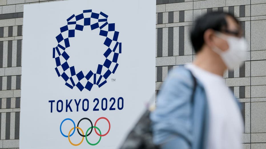 A man walks past a Tokyo 2020 banner on a building in