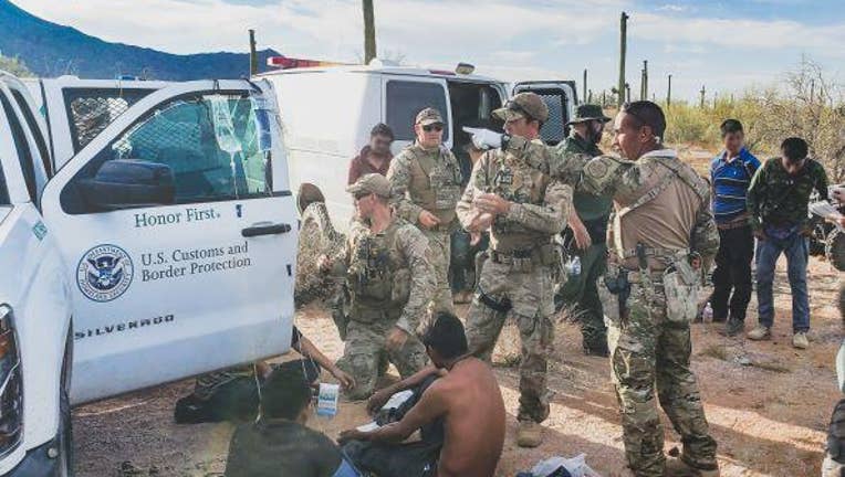 Border patrol agents gathered around migrants