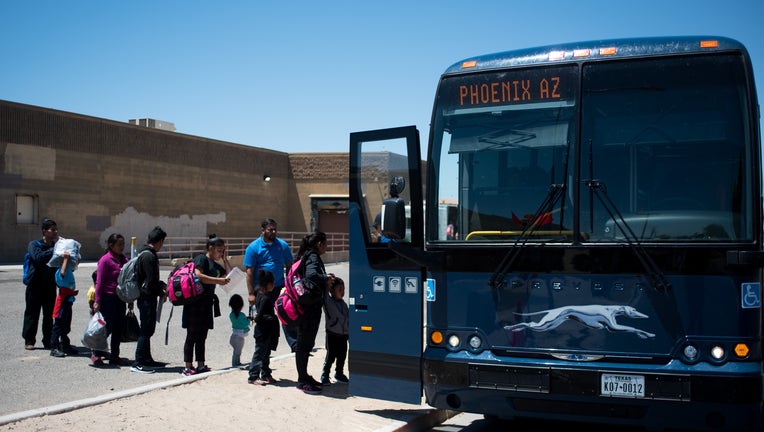 Buses idle in the noon sun waiting to take migrant families to reunite with their families in Yuma