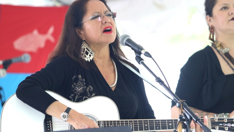 Singer, songwriter and guitarist Joanne Shenandoah is shown performing on stage.