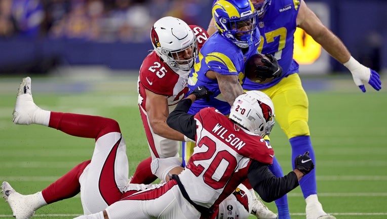 Cam Akers #23 of the Los Angeles Rams runs with the ball as Zaven Collins #25 and Marco Wilson #20 of the Arizona Cardinals defend in the first quarter of the NFC Wild Card Playoff game at SoFi Stadium in Inglewood, California. (Photo by Harry How/Getty Images)