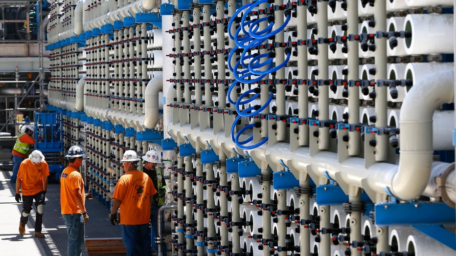 Employees work at a water desalination plant. The plant is an interconnected system of 2,500 reverse osmosis pressure vessels that reportedly will have the capacity to filter 50 million gallons of sea water per day. (Photo by Don Bartletti/Los Angeles Times via Getty Images)