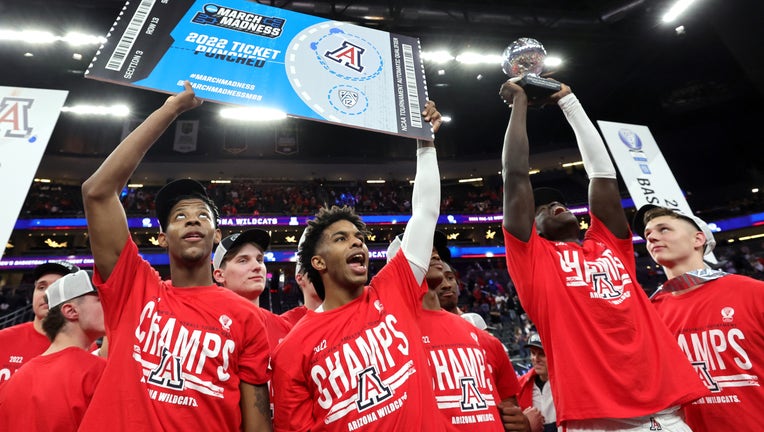 Dalen Terry #4 and Justin Kier #5 of the Arizona Wildcats hold up a ceremonial NCAA tournament ticket with a team sticker on it as Oumar Ballo #11 holds up the championship trophy as Pelle Larsson #3 looks on after their 84-76 victory over the UCLA Bruins to win the Pac-12 Conference basketball tournament championship game at T-Mobile Arena on March 12, 2022 in Las Vegas, Nevada. 