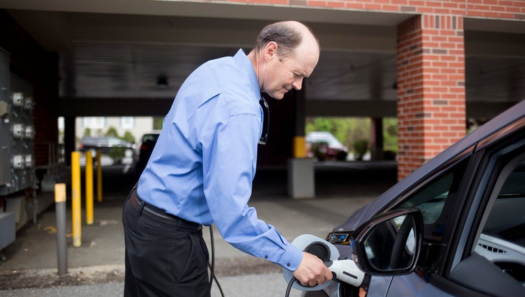 A man charging an electric car. (Staff photo by Brianna Soukup/Portland Portland Press Herald via Getty Images)