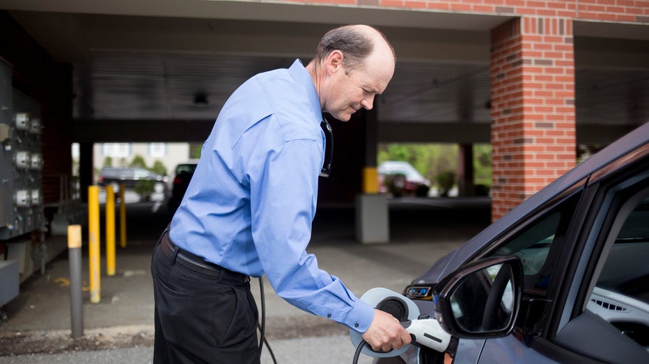 A man charging an electric car. (Staff photo by Brianna Soukup/Portland Portland Press Herald via Getty Images)
