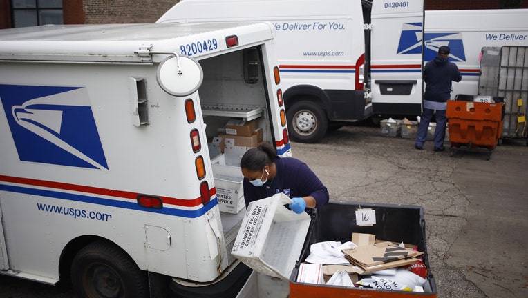 Workers load mail into delivery vehicles outside a United States Postal Service (USPS) distribution center (Photographer: Luke Sharrett/Bloomberg via Getty Images)