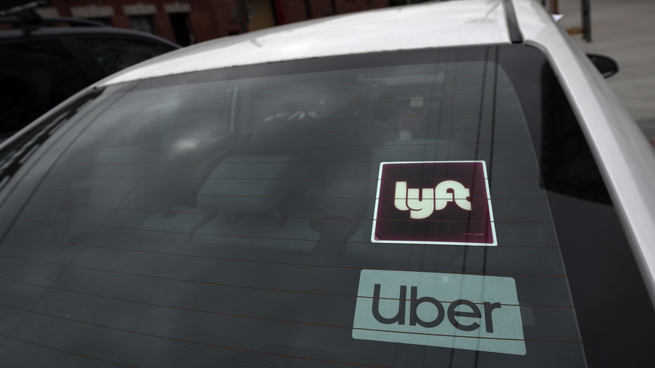 A car with a Lyft and Uber sticker on its windshield, indicating the driver provides rides for both rideshare services. (Photo by ROBYN BECK/AFP via Getty Images)