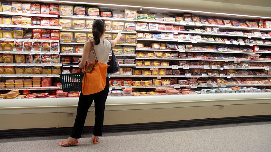 A woman looking at packets of sausages in Publix grocery store.