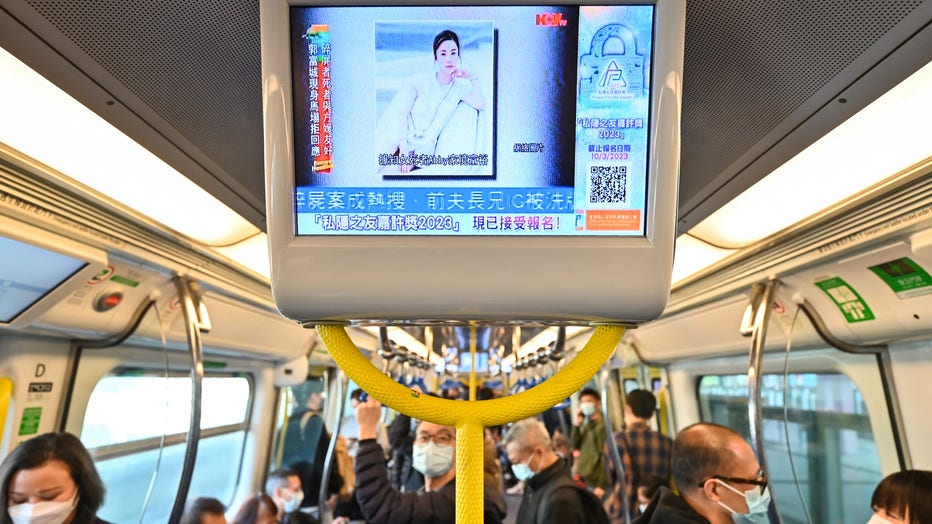 People watch a screen on a Hong Kong train showing news about model and influencer Abby Choi, whose partial remains were found by the police at a house. (Photo by PETER PARKS/AFP via Getty Images)