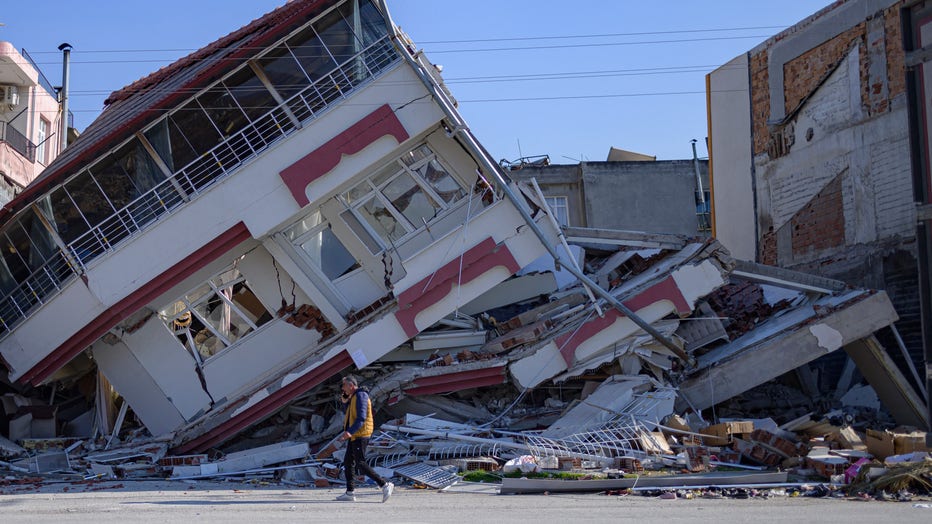 A man walks in front of a destroyed building in Samandag, south of Hatay, ten days after a 7.8-magnitude struck the border region of Turkey and Syria. (Photo by YASIN AKGUL/AFP via Getty Images)