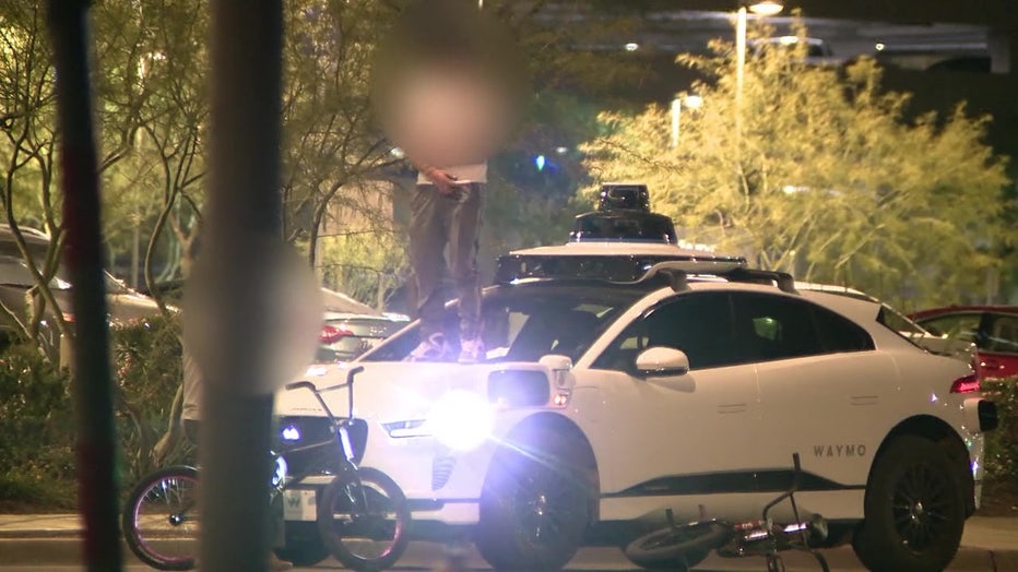 A screenshot from a video showing the teen jumping on top of a driverless Waymo car in Phoenix, Arizona.