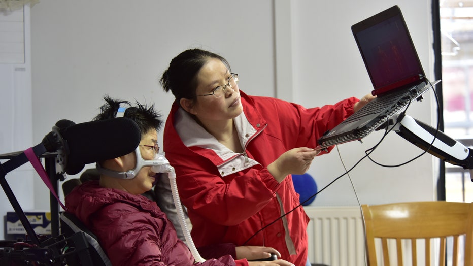 An ALS patient wears a ventilator at home and uses an eye-control device to write an article to communicate with her patients via livestream. (CFOTO/Future Publishing via Getty Images)