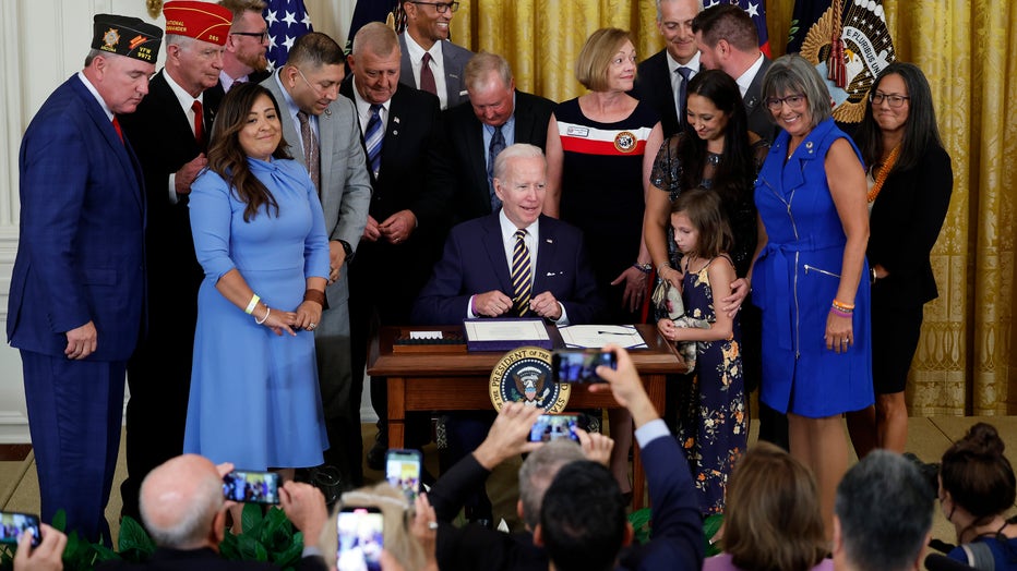 U.S. President Joe Biden prepares to sign the PACT Act during a ceremony with Veterans Affairs Secretary Denis McDonough (R) and others in the East room of the White House on August 10, 2022.