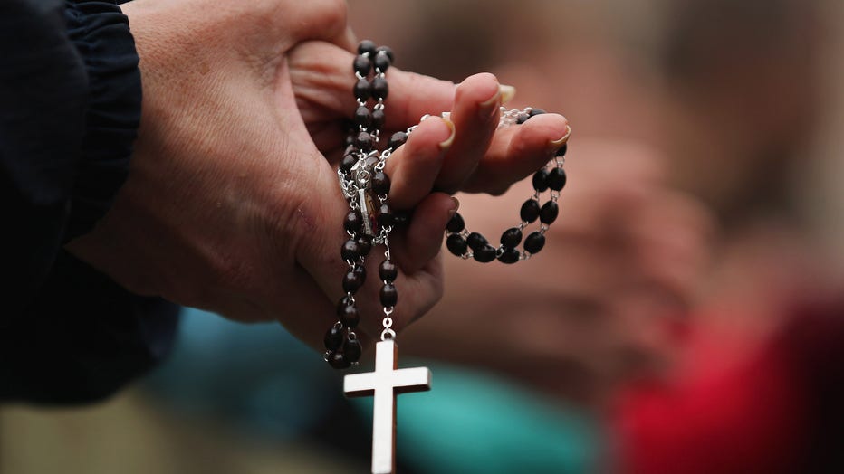A woman holds rosary beads while she prays. (Photo by Dan Kitwood/Getty Images)
