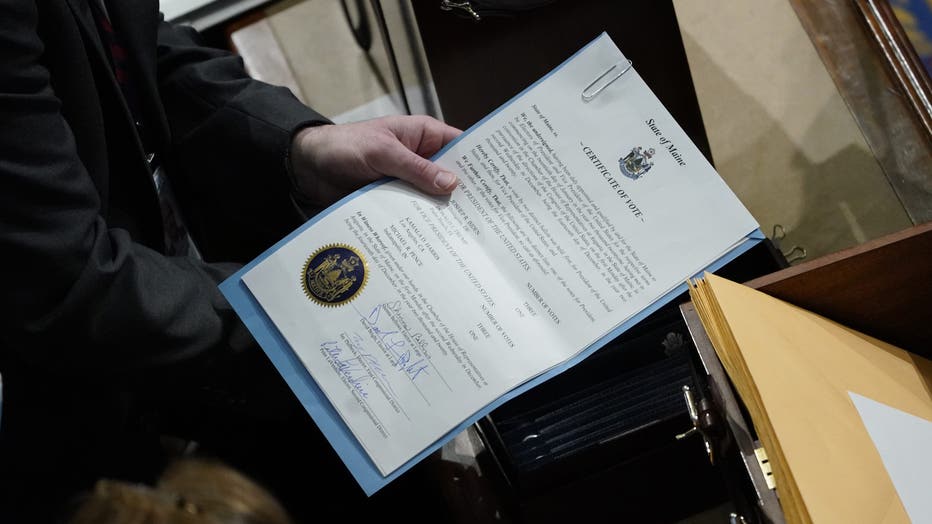 A congressional aide examines electoral college votes from the State of Maine in the Chamber of the U.S. House of Representatives in 2021. (Photo by Drew Angerer/Getty Images)