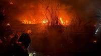 Wind-driven fire burns structures, power poles