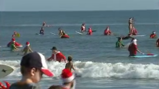 Hundreds of Santas take on surfing